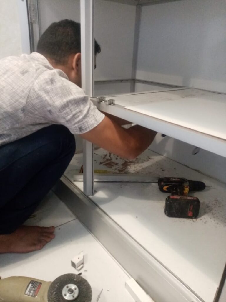 صورة تظهر فني متخصص أثناء تنفيذ أعمال صيانة مطابخ حي النعيم بجدة، حيث يقوم بتصليح الأبواب وتغيير المفصلات التالفة لضمان عودة المطبخ لحالته المثالية بأعلى جودة.