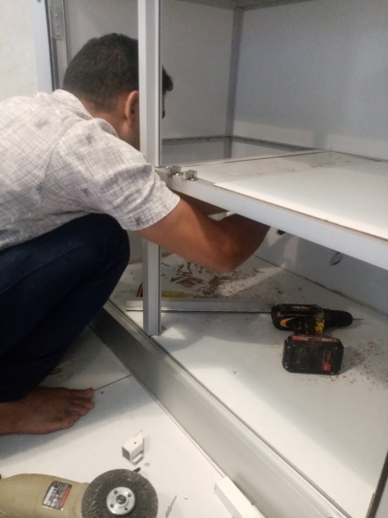 صورة تظهر فني متخصص أثناء تنفيذ أعمال صيانة مطابخ حي النعيم بجدة، حيث يقوم بتصليح الأبواب وتغيير المفصلات التالفة لضمان عودة المطبخ لحالته المثالية بأعلى جودة 