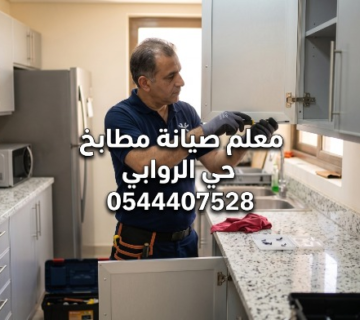 معلم صيانة مطابخ يعمل على إصلاح مفصلة باب دولاب ألمنيوم رمادي  يرتدي الفني قميصا أزرق وقفازات ويستخدم مفك براغي  مكتوب على الصورة: معلم صيانة مطابخ حي الروابي 0544407528  يظهر في الخلفية مطبخ حديث بأسطح رخامية وصندوق أدوات مفتوح 